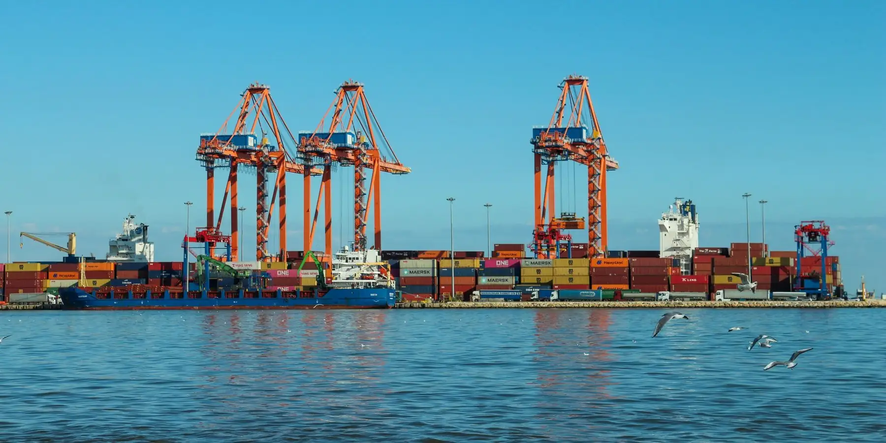 Port cranes and a cargo ship under a blue sky